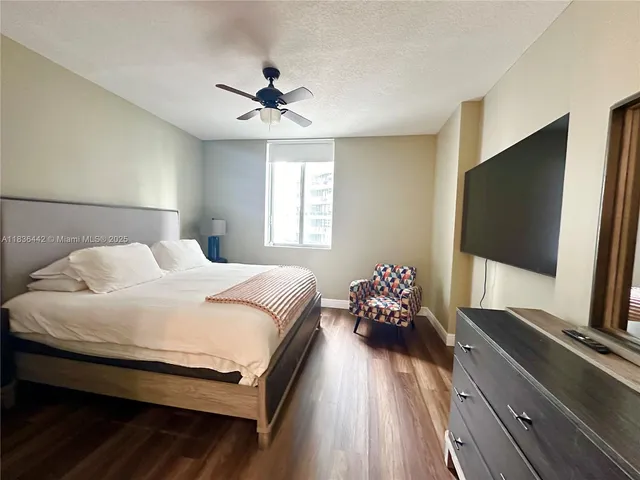 a bedroom with a large bed and a flat tv screen