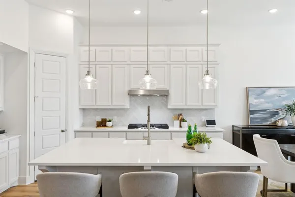 a kitchen with stainless steel appliances granite countertop a sink a stove and white cabinets with wooden floor