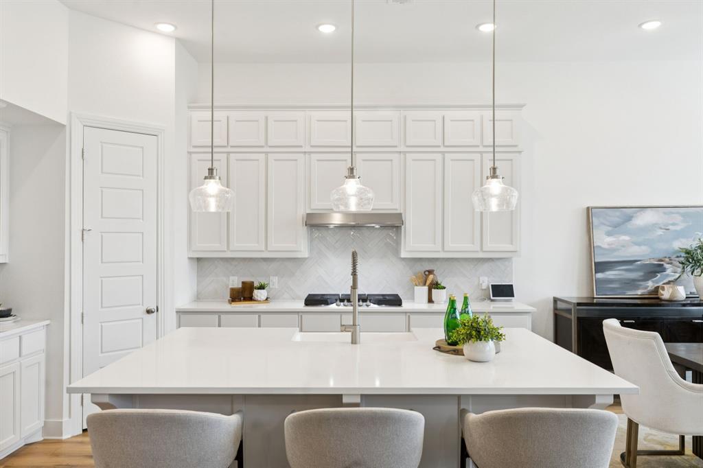 a kitchen with stainless steel appliances granite countertop a sink a stove and white cabinets with wooden floor