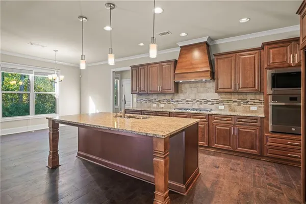 a kitchen with stainless steel appliances granite countertop wooden cabinets a stove a sink and a large window