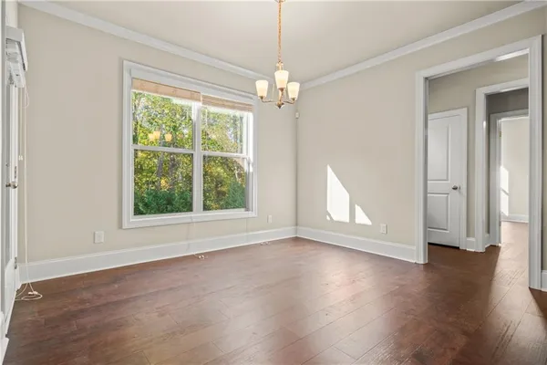 an empty room with wooden floor chandelier and windows