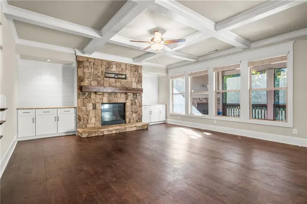 an empty room with wooden floor fireplace and windows