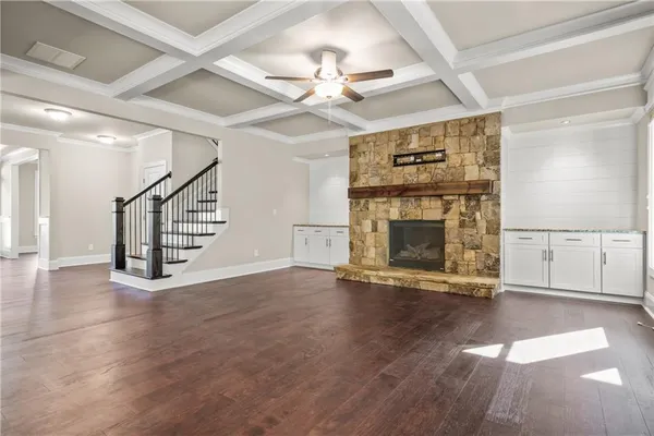 an empty room with wooden floor fireplace and windows