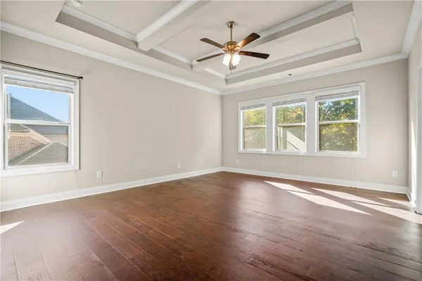 an empty room with wooden floor ceiling fan and windows