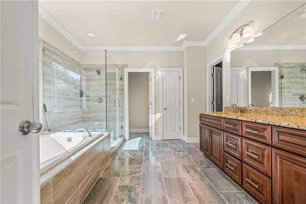 a spacious bathroom with a granite countertop tub sink shower and mirror