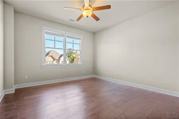an empty room with windows and chandelier fan