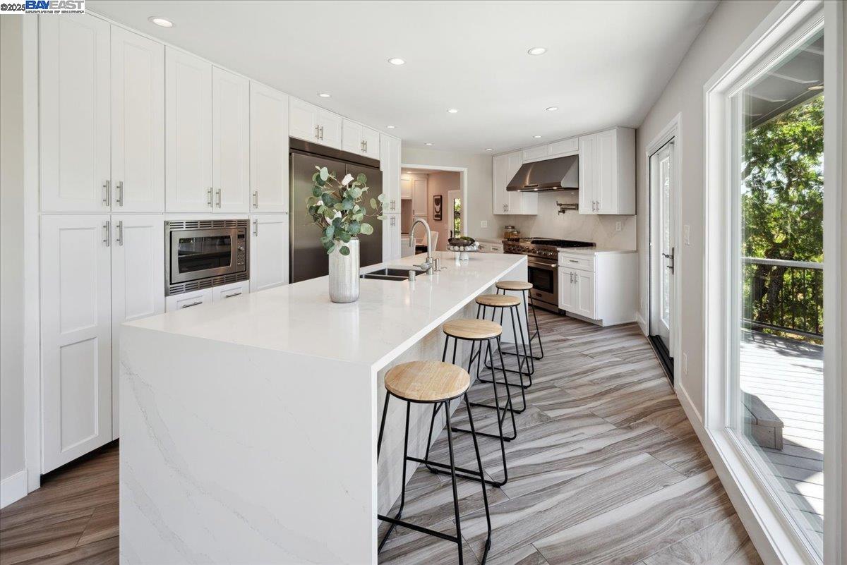 325 Bollinger Estates Court San Ramon, CA 94583 - Photo 12 of 59 a kitchen with stainless steel appliances a stove top oven a refrigerator a dining table and chairs with wooden floor