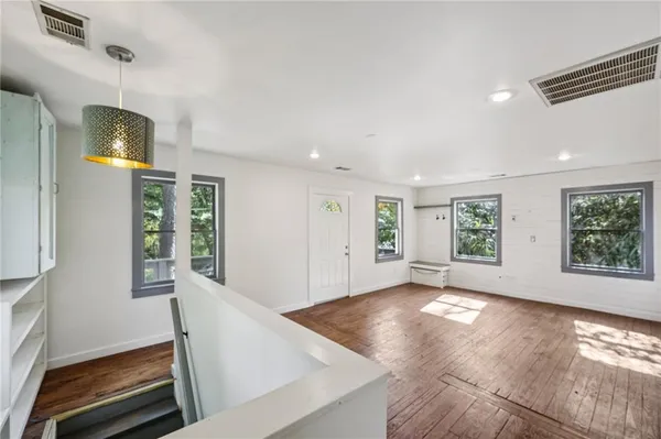 a view of an empty room with window and wooden floor