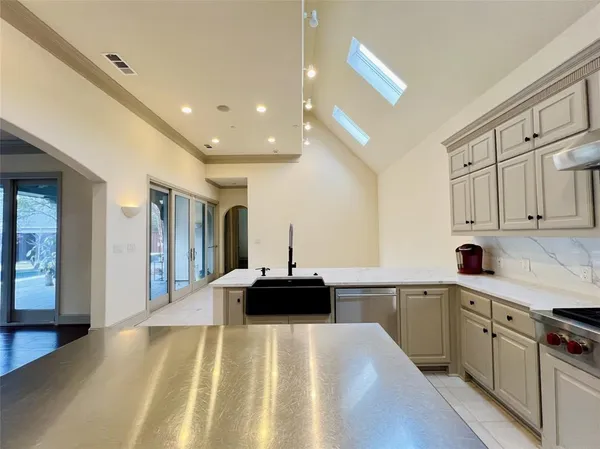 a kitchen with a sink dishwasher a stove and white cabinets with wooden floor