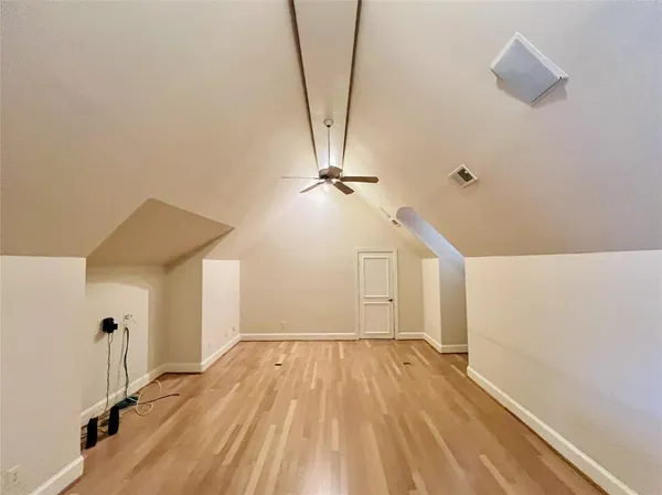 an empty room with wooden floor and fan