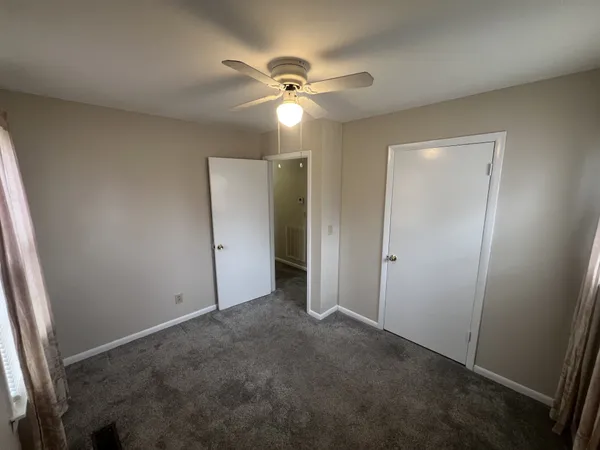 an empty room with closet and a ceiling fan
