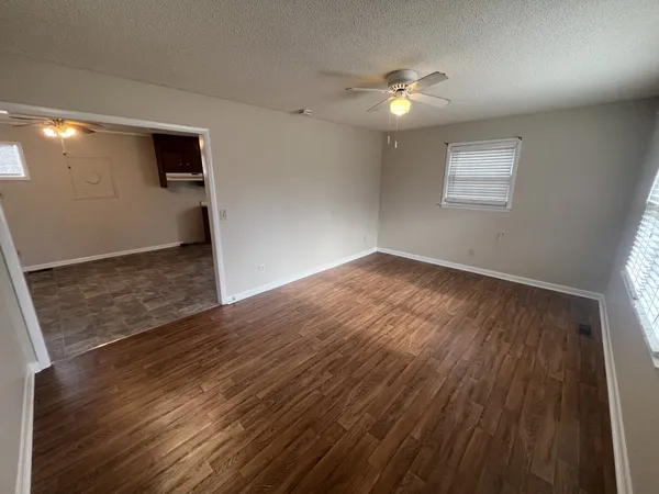 a view of an empty room with wooden floor and a window
