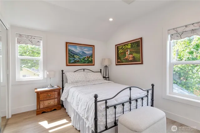 a bedroom with a bed a painting and a window