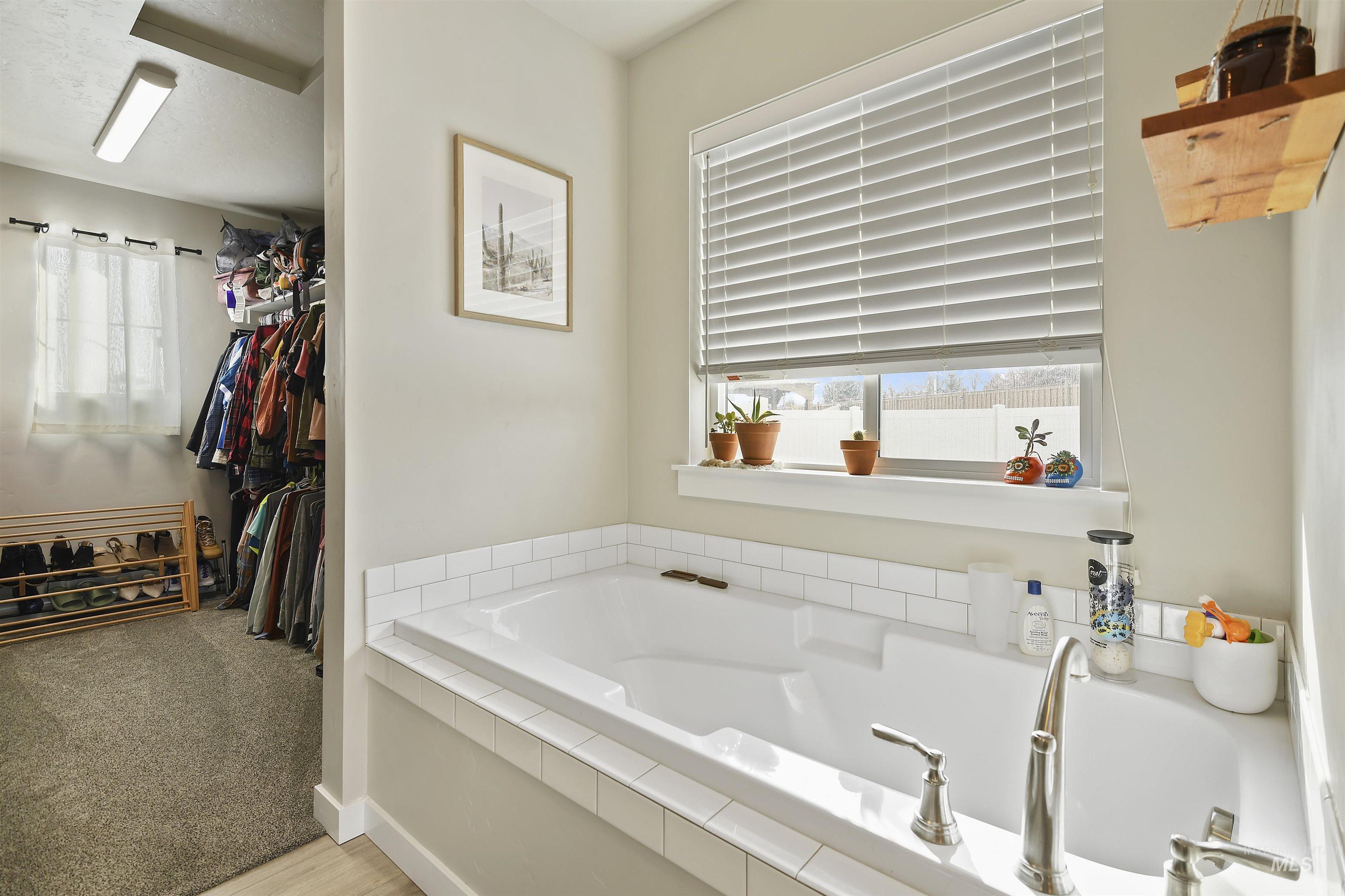 13472 Deodar Street Caldwell, ID 83607 - Photo 14 of 22 Bathroom featuring light carpet, a bath, plenty of natural light, and a walk in closet