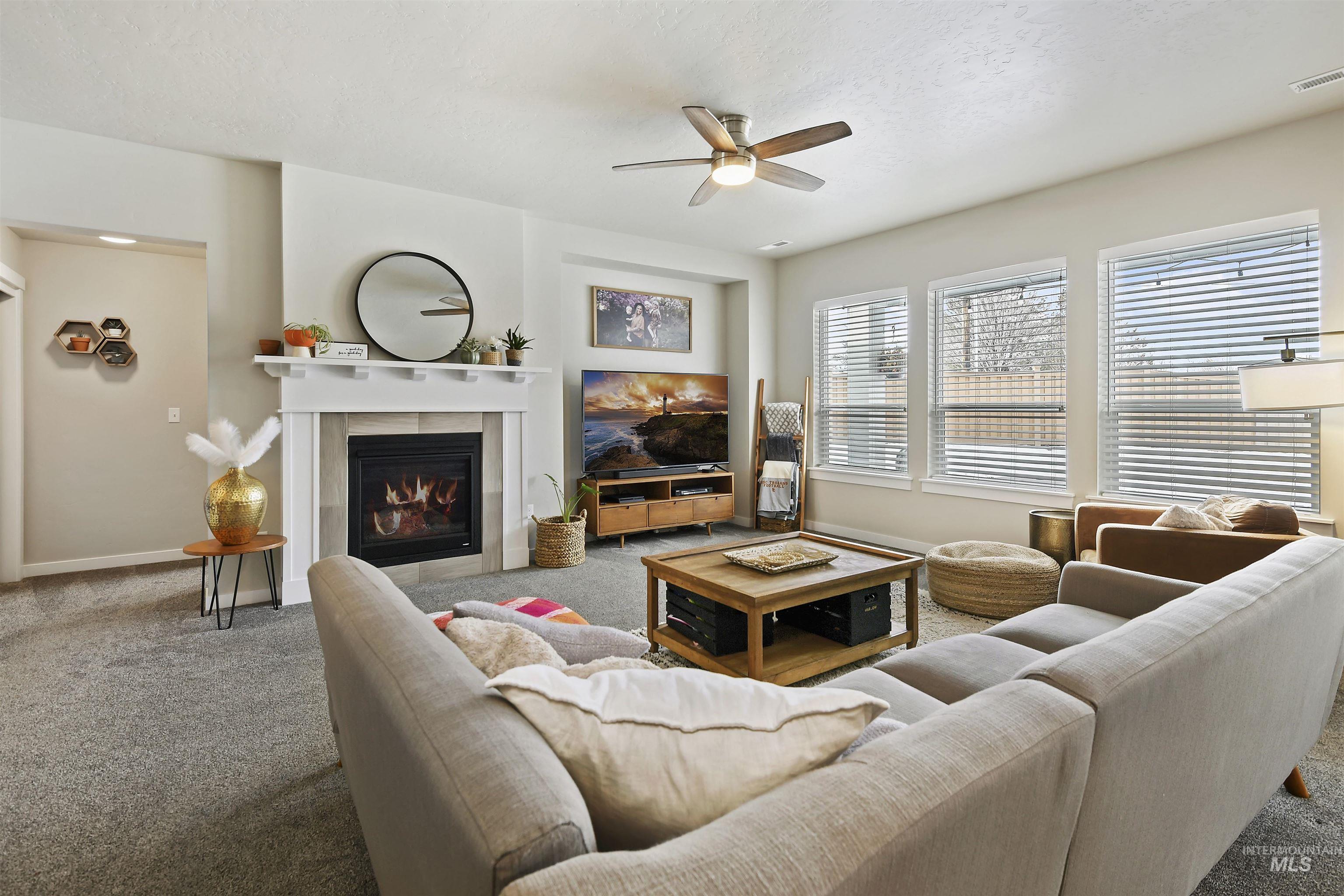 13472 Deodar Street Caldwell, ID 83607 - Photo 4 of 22 Carpeted living area featuring a glass covered fireplace and a ceiling fan