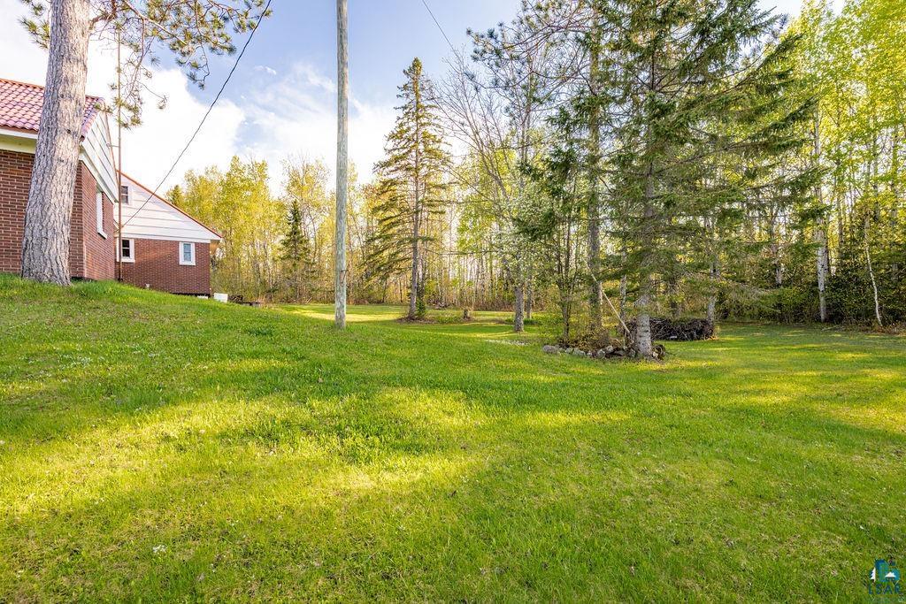 4543 County Road East South Range, WI 54874 - Photo 35 of 43 Expansive green lawn surrounded by mature trees, featuring a red brick exterior with a red tile roof