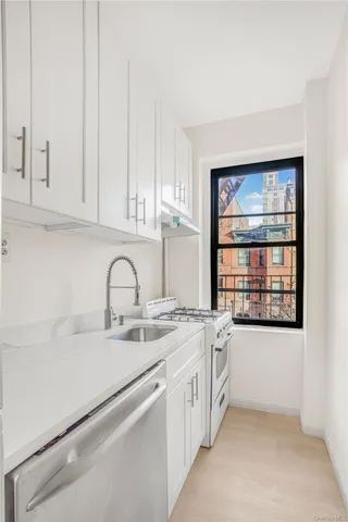 a utility room with stainless steel appliances granite countertop a sink and a window