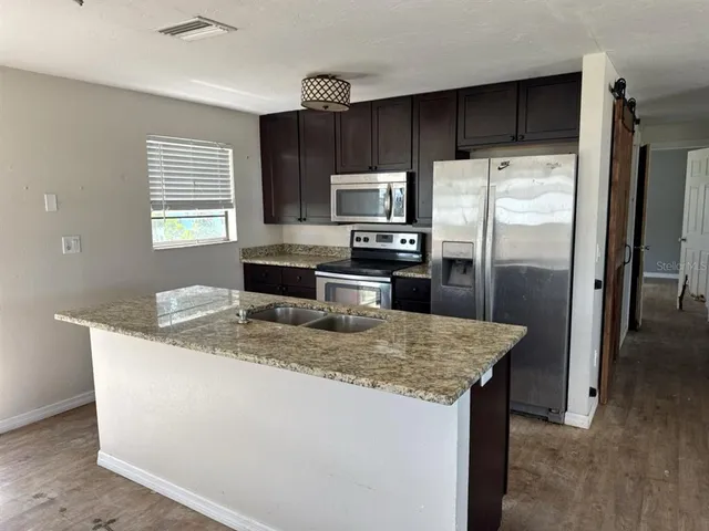 a kitchen with kitchen island a refrigerator sink and microwave