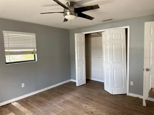 a view of empty room with wooden floor and fan