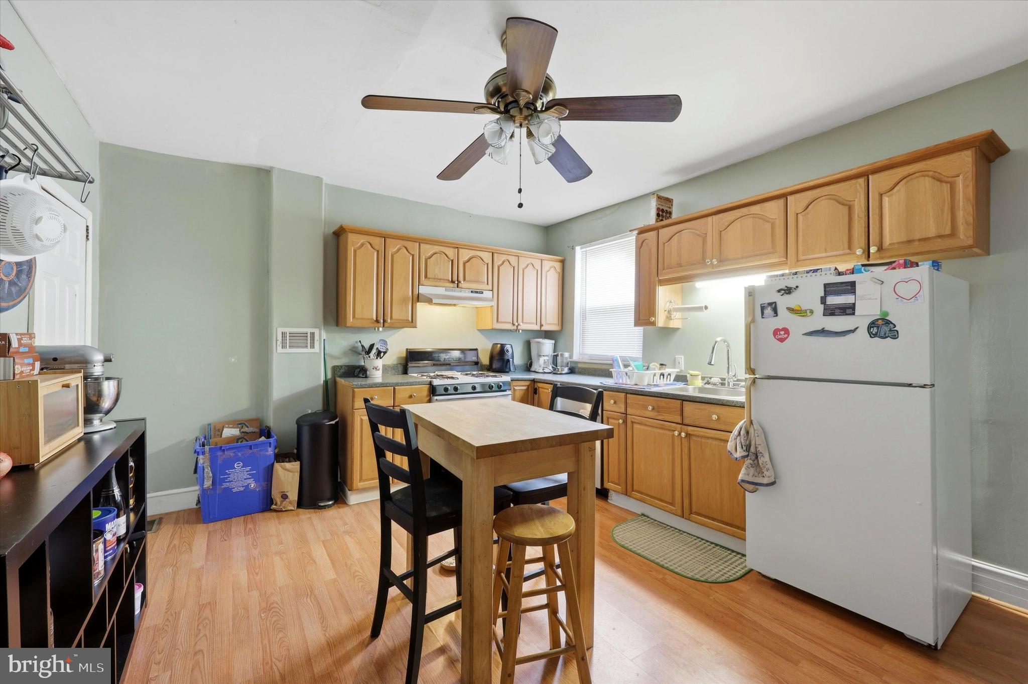 2442 East Gordon Street Philadelphia, PA 19125 - Photo 17 of 40 a kitchen with a refrigerator a stove a sink dishwasher and a dining table with wooden floor