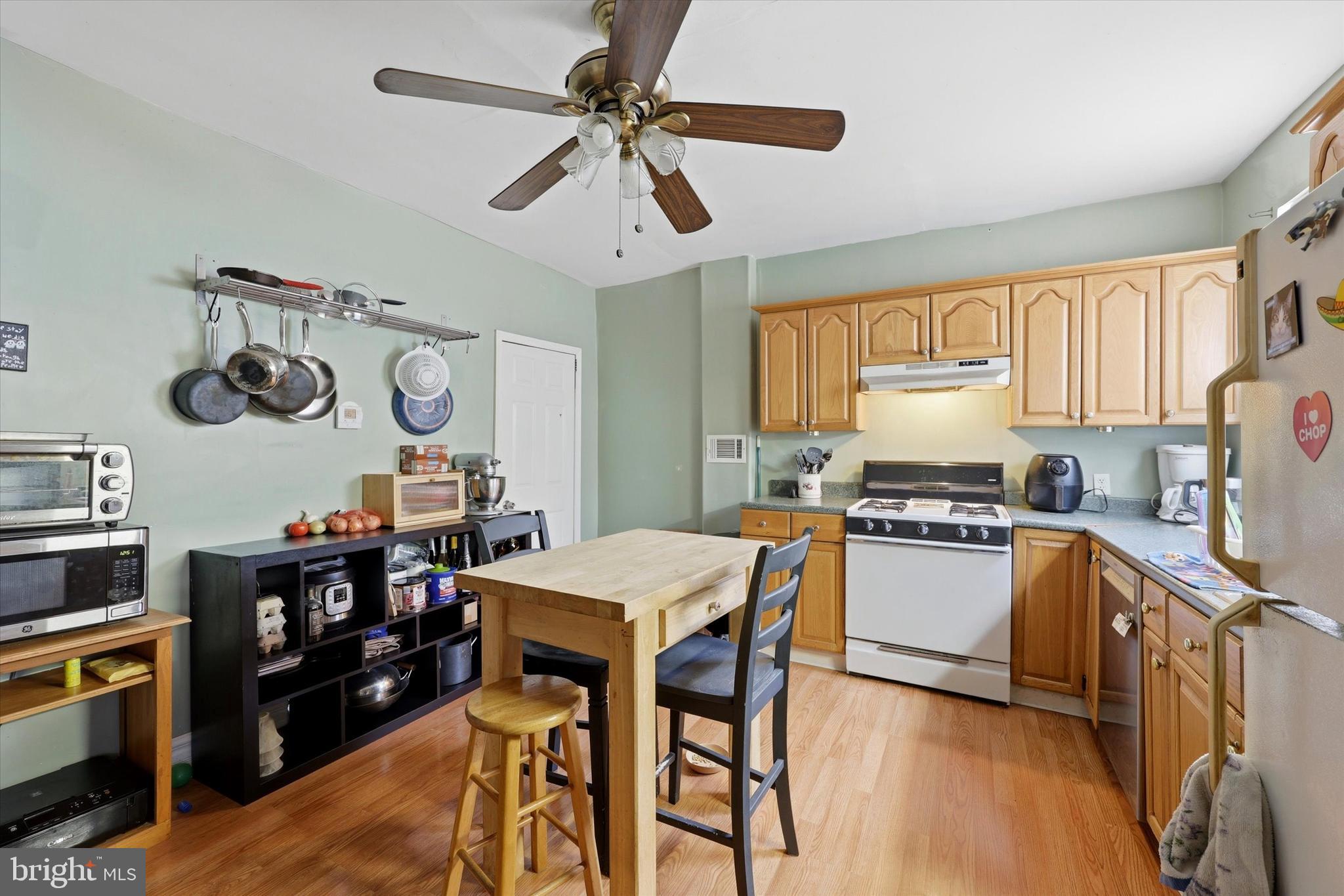 2442 East Gordon Street Philadelphia, PA 19125 - Photo 4 of 40 a kitchen with stainless steel appliances granite countertop a stove top oven a refrigerator a dining table and chairs with wooden floor