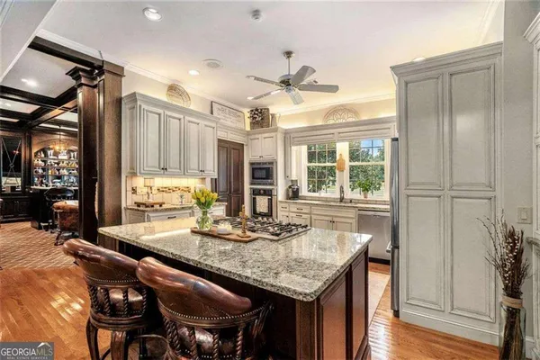 a kitchen with stainless steel appliances granite countertop a sink a stove a refrigerator cabinets and dining table