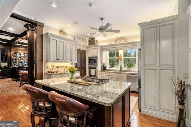 a kitchen with stainless steel appliances granite countertop a sink a stove a refrigerator cabinets and dining table