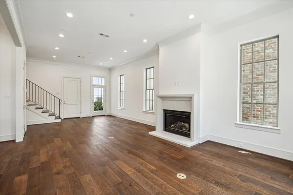 a view of an empty room with wooden floor fireplace and a window