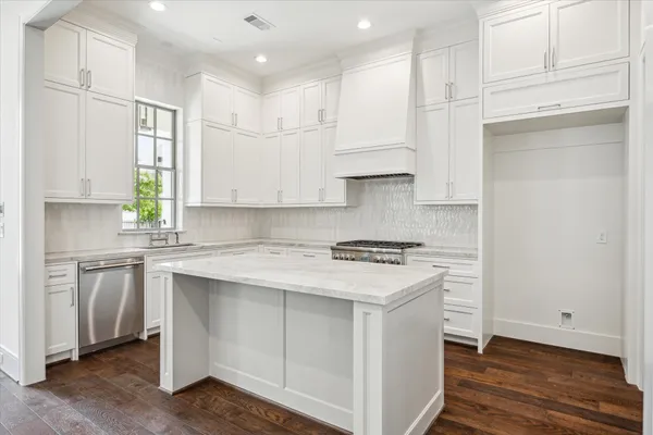 a kitchen with stainless steel appliances granite countertop a stove a sink and white cabinets