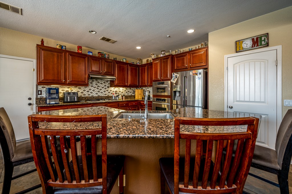 18668 Alderbrook Drive Riverside, CA 92508 - Photo 10 of 28 a kitchen with stainless steel appliances granite countertop a stove top oven a refrigerator and wooden cabinets