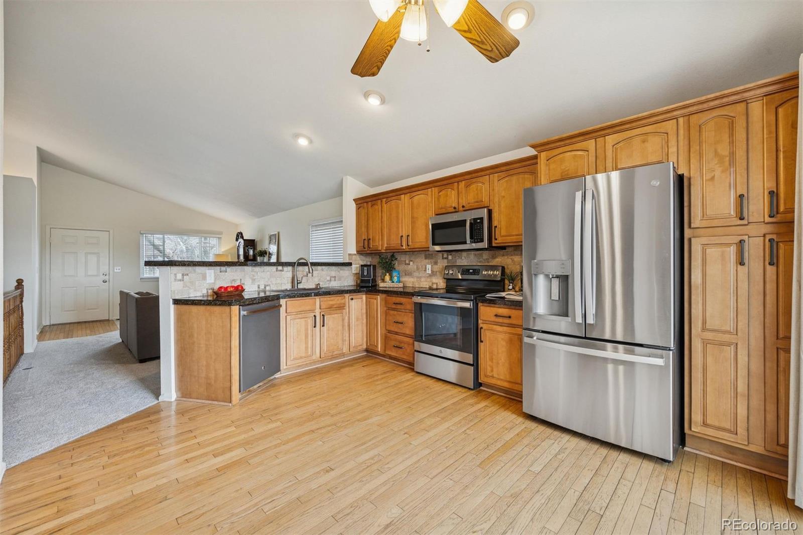 9471 Burlington Lane Highlands Ranch, CO 80130 - Photo 12 of 50 a kitchen with stainless steel appliances a refrigerator and wooden floor