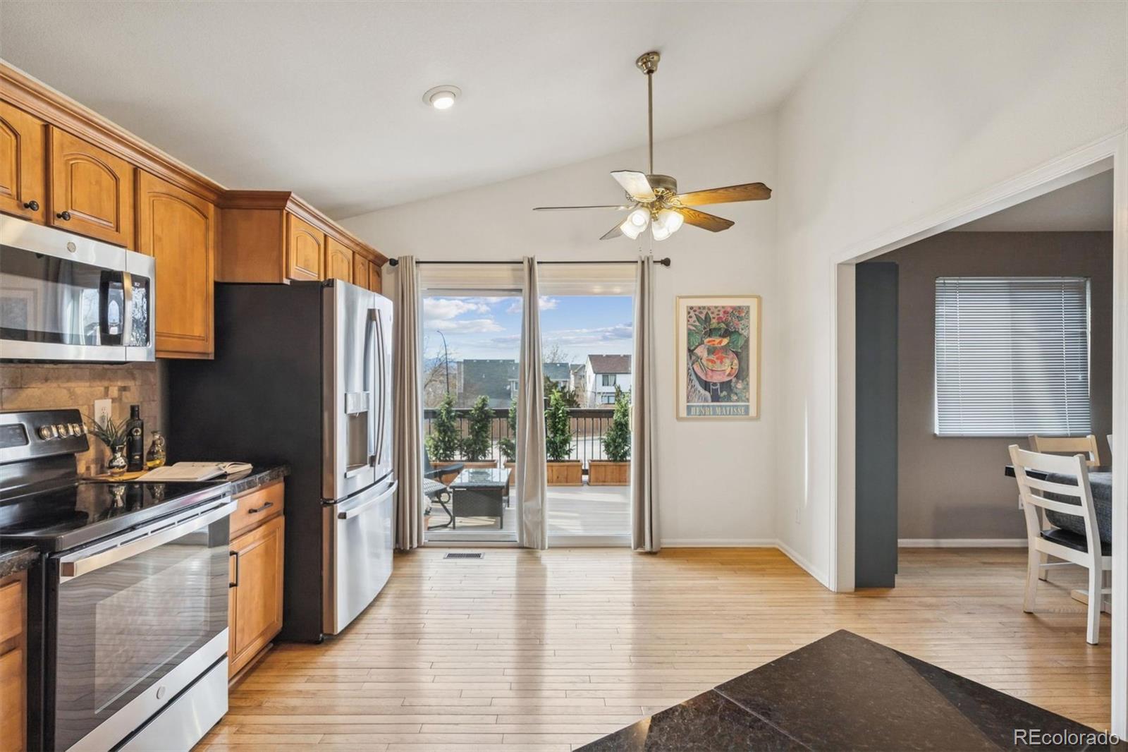 9471 Burlington Lane Highlands Ranch, CO 80130 - Photo 14 of 50 a kitchen with stainless steel appliances granite countertop a refrigerator a stove a sink dishwasher a refrigerator a dining table and chairs with wooden floor