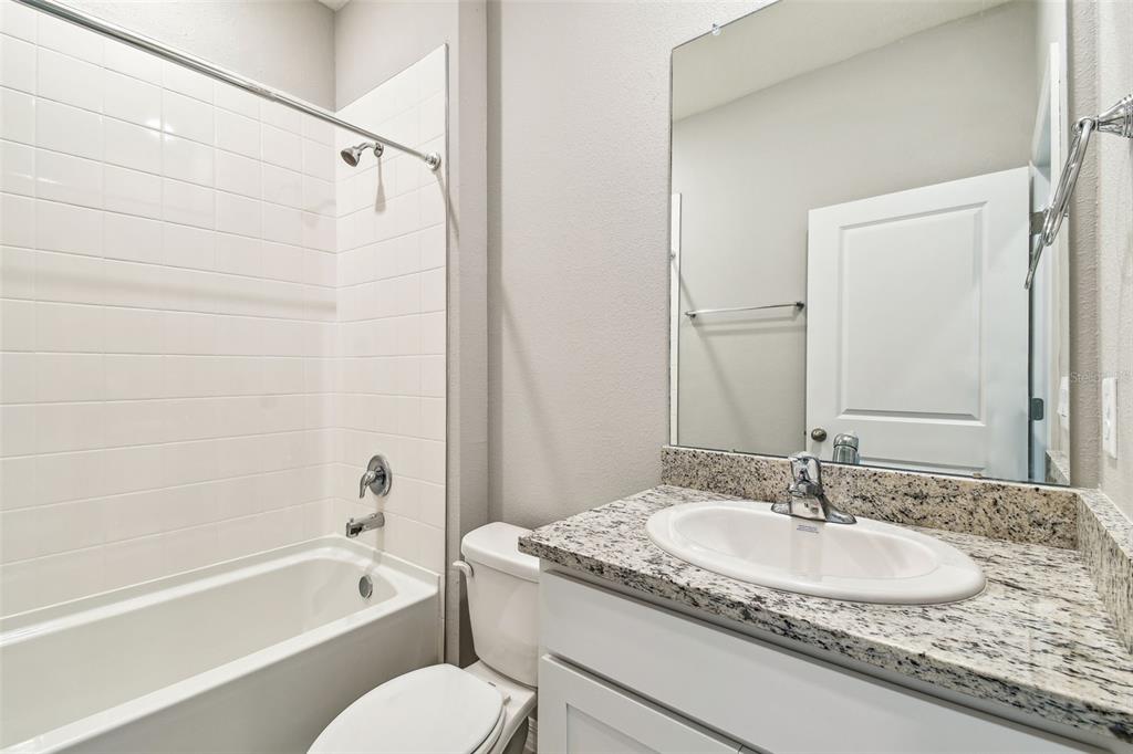 33870 Field Maple Loop Wesley Chapel, FL 33545 - Photo 13 of 38 a bathroom with a granite countertop sink a toilet and bathtub