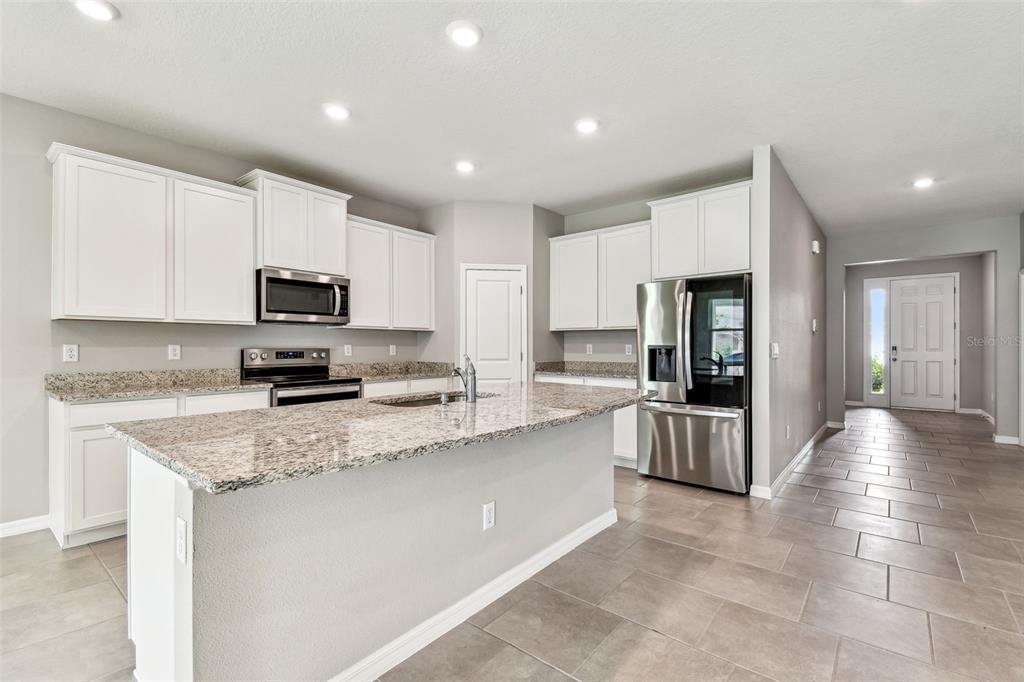 33870 Field Maple Loop Wesley Chapel, FL 33545 - Photo 5 of 38 a kitchen with stainless steel appliances granite countertop a refrigerator sink and stove