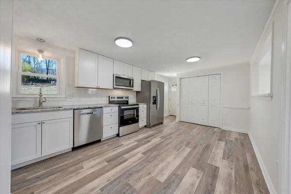 a kitchen with granite countertop a sink stainless steel appliances and white cabinets