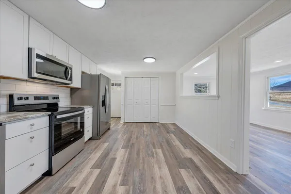 a kitchen with granite countertop wooden floors a sink stainless steel appliances and cabinets