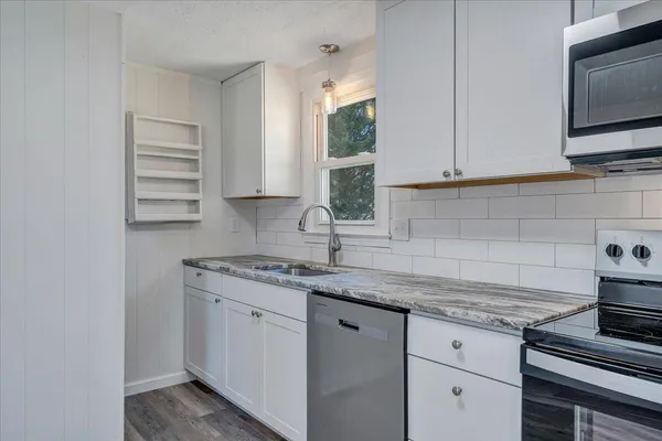 a kitchen with granite countertop a sink stainless steel appliances and cabinets