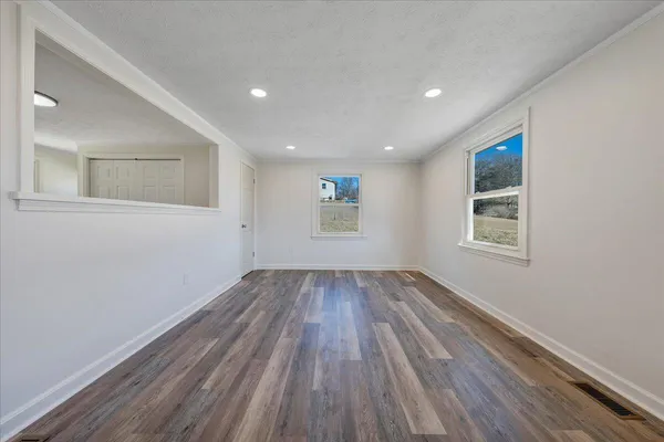 a view of an empty room with wooden floor and a window