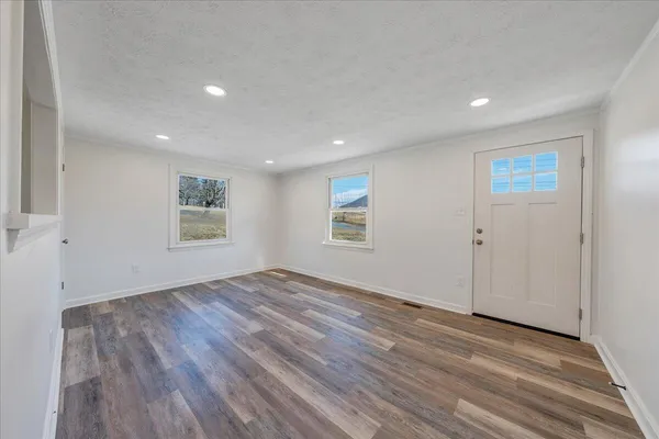 an empty room with wooden floor and windows