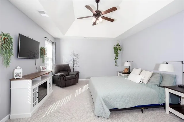 a bedroom with a large bed a flat tv screen and a fireplace