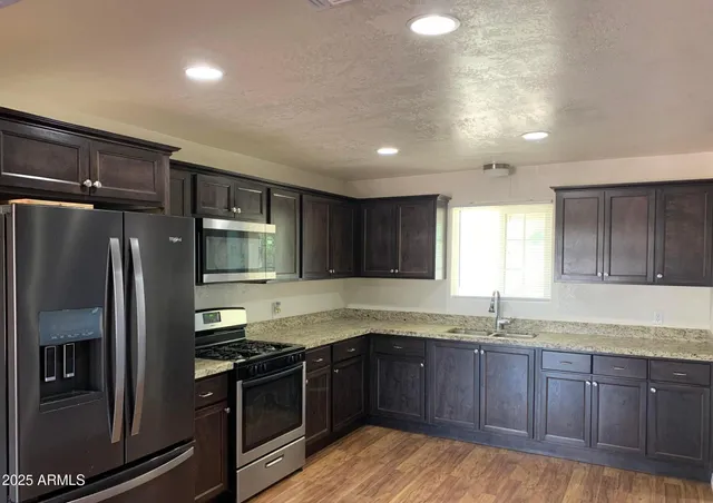 a kitchen with granite countertop a sink stainless steel appliances and cabinets