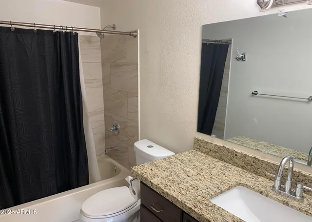a bathroom with a granite countertop sink a toilet and shower