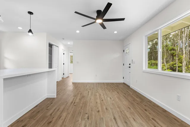 a view of an empty room with a window and wooden floor