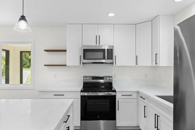 a kitchen with white cabinets and black appliances