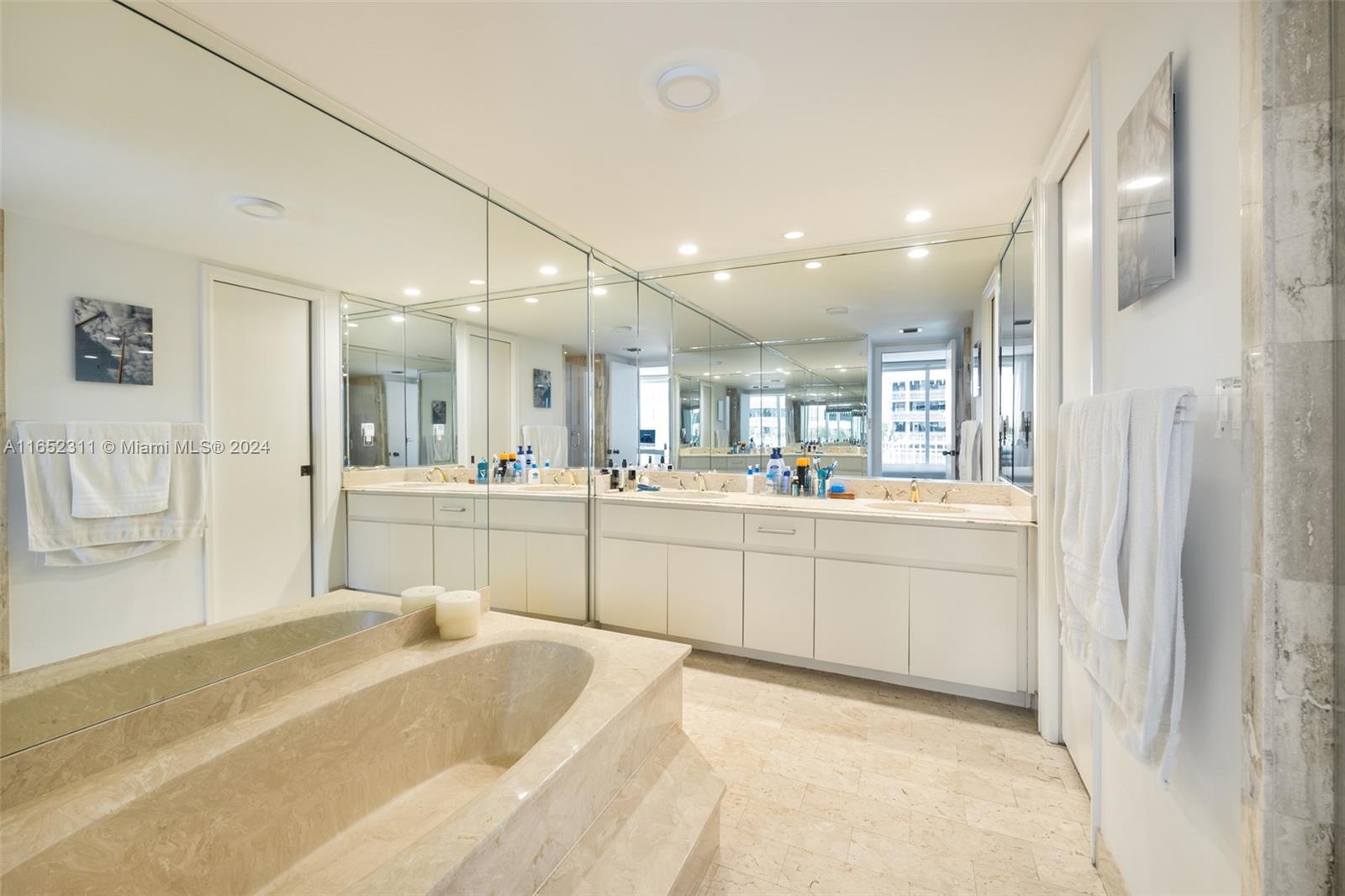 2 Grove Isle Drive, Unit B402 Miami, FL 33133 - Photo 16 of 35 a bathroom with a tub sink and mirror