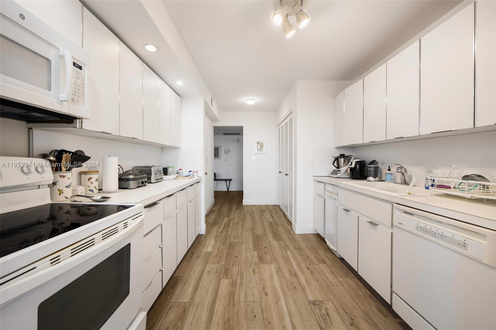 2 Grove Isle Drive, Unit B402 Miami, FL 33133 - Photo 23 of 35 a kitchen with granite countertop white cabinets and white appliances