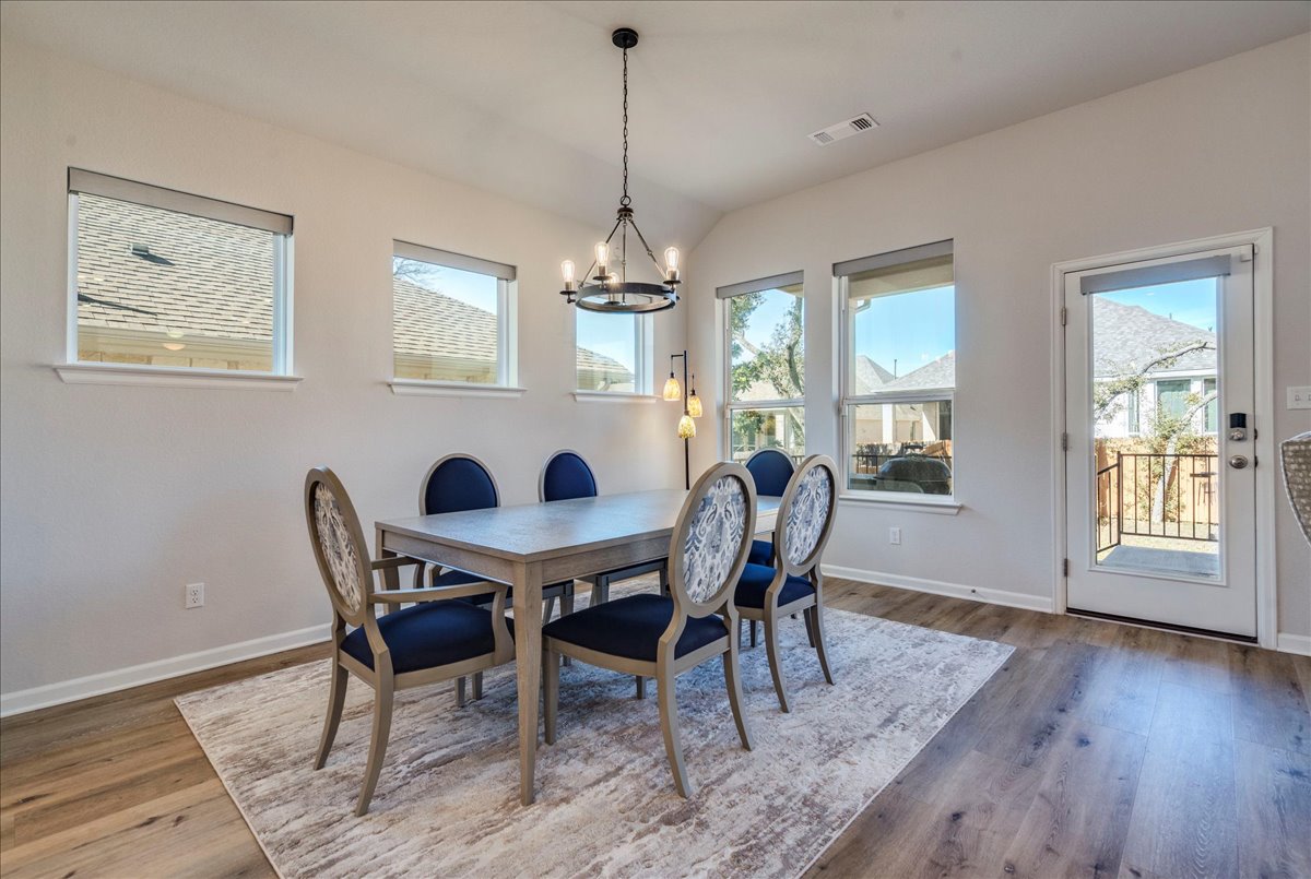 200 Christi Court Kyle, TX 78640 - Photo 15 of 40 Dining space with wood finished floors, a chandelier, and vaulted ceiling
