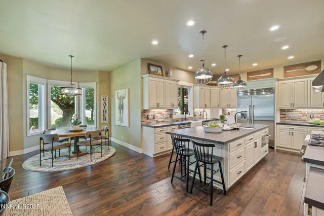 a kitchen with a dining table chairs wooden floor and appliances