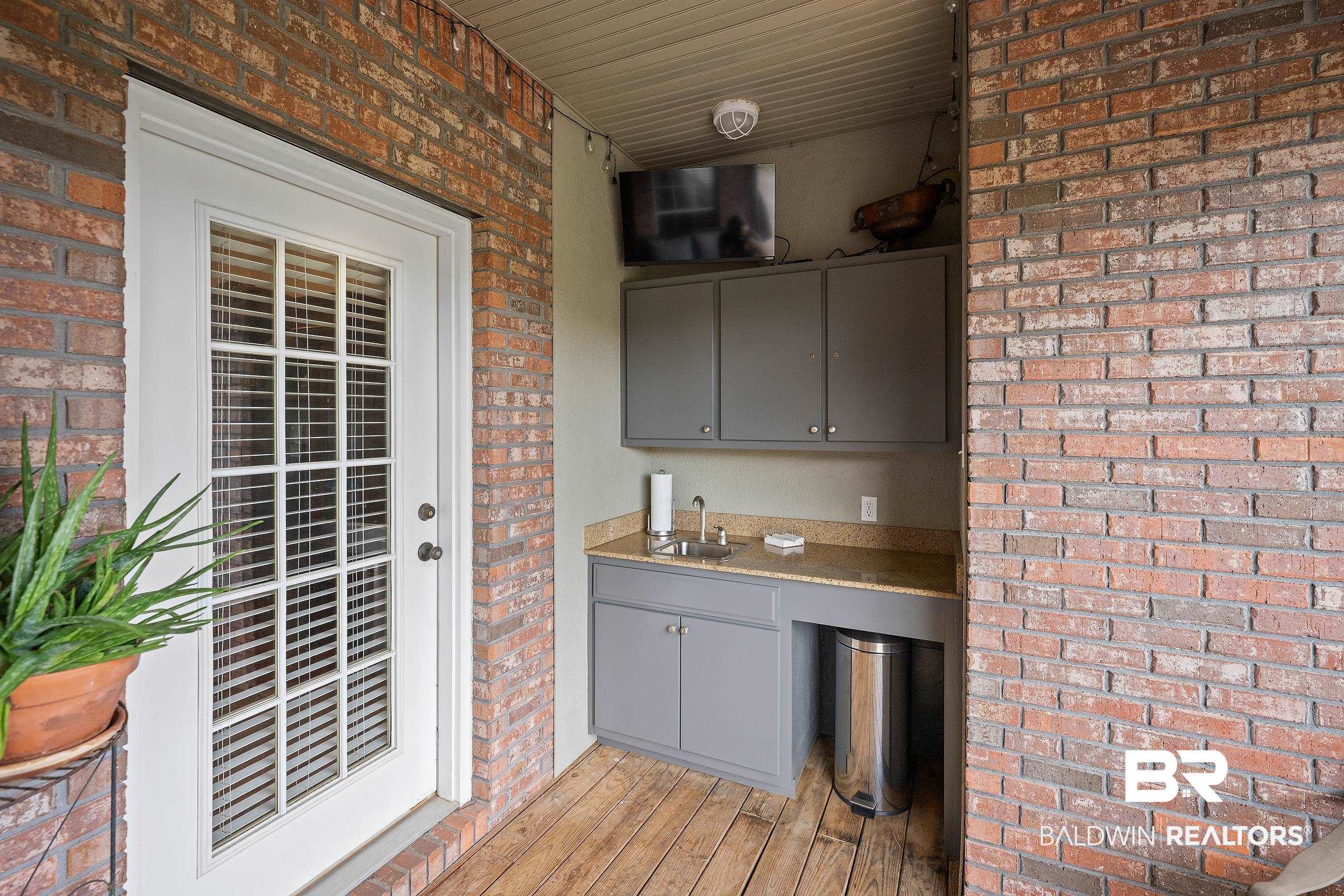 197 Morning Ridge Road Monroeville, AL 36460 - Photo 45 of 51 Outdoor kitchen area with wood-finish flooring, brick wall construction, and a white glass-paneled door