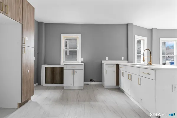 a view of a kitchen with white cabinets with wooden floor